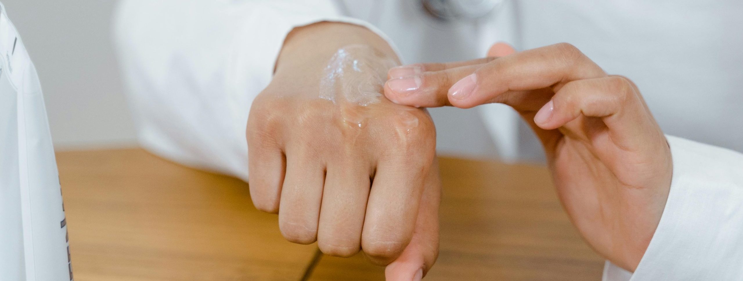 Close-up of a doctor applying lotion on their hand, focusing on skincare.